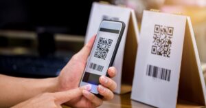 A customer holds their phone as they take a photo of the QR code listed on a piece of paper. The paper is on a table tent.
